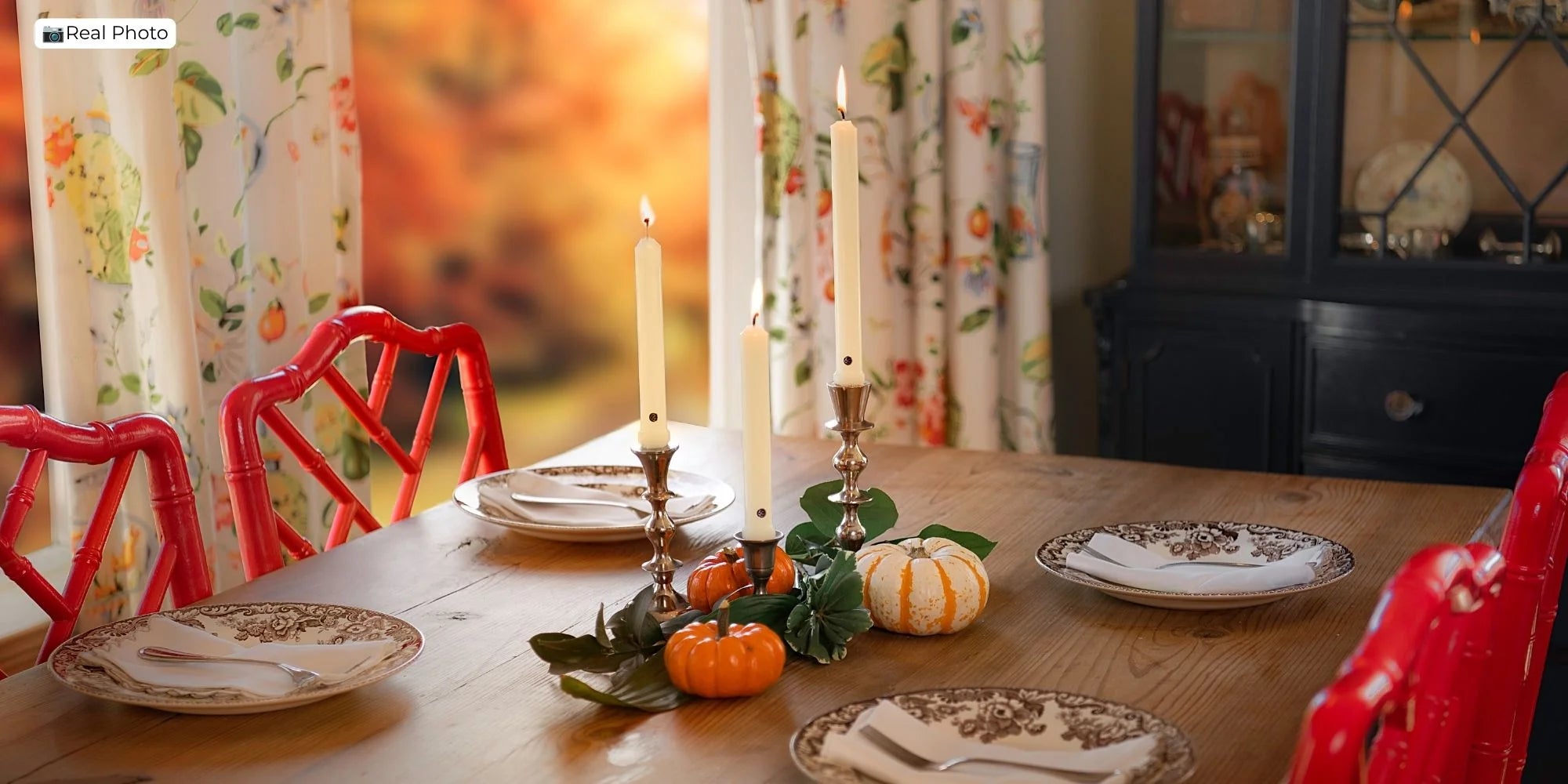 Fall table set with taper candles, pumpkins, foliage, and patterned plates
